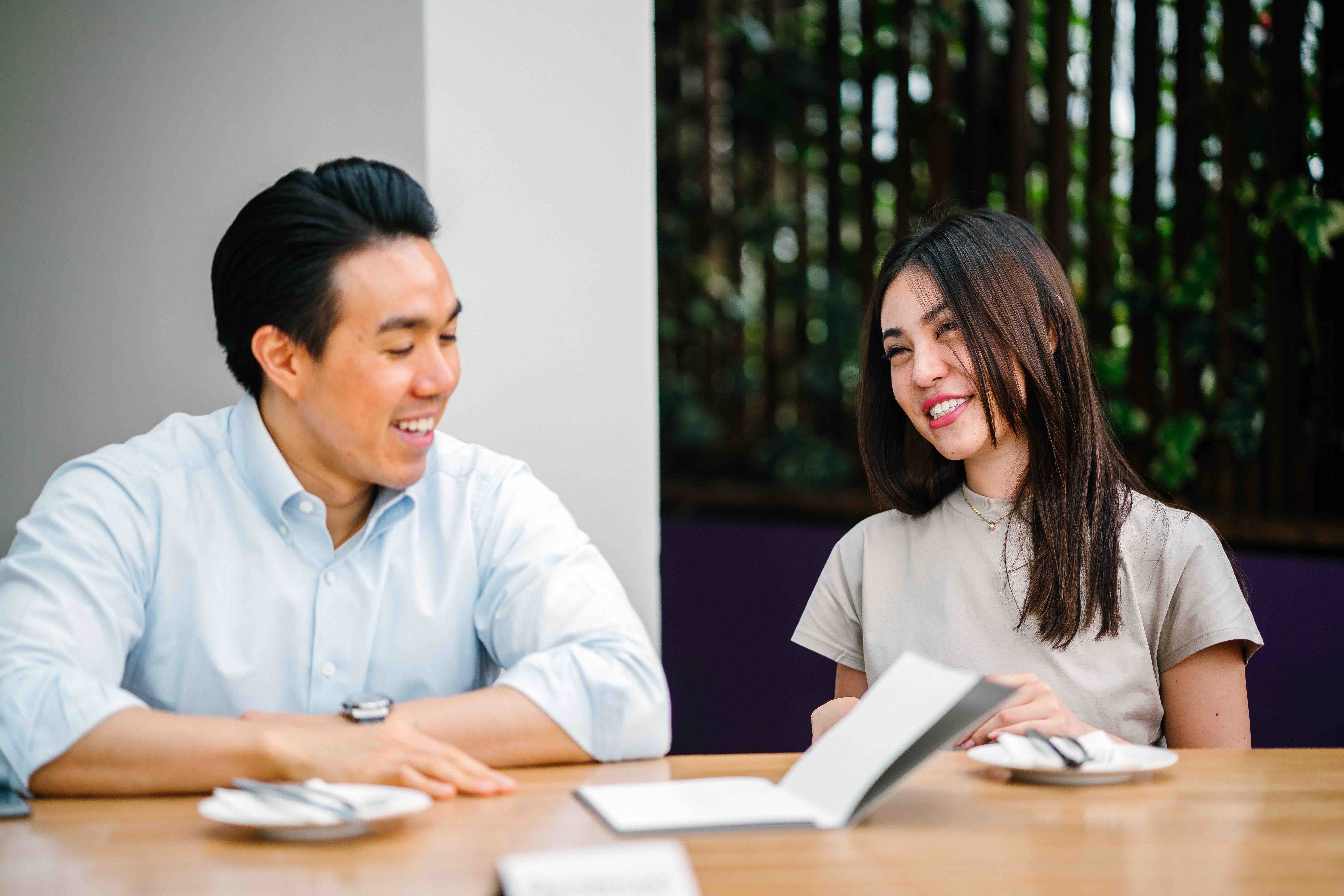 Man and woman sitting side by side at table in front of an open notebook